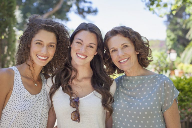 Mother and daughters hugging outdoors